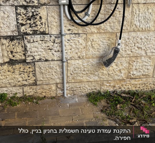 עמדת טעינה חשמלית עם כבל על קיר אבן